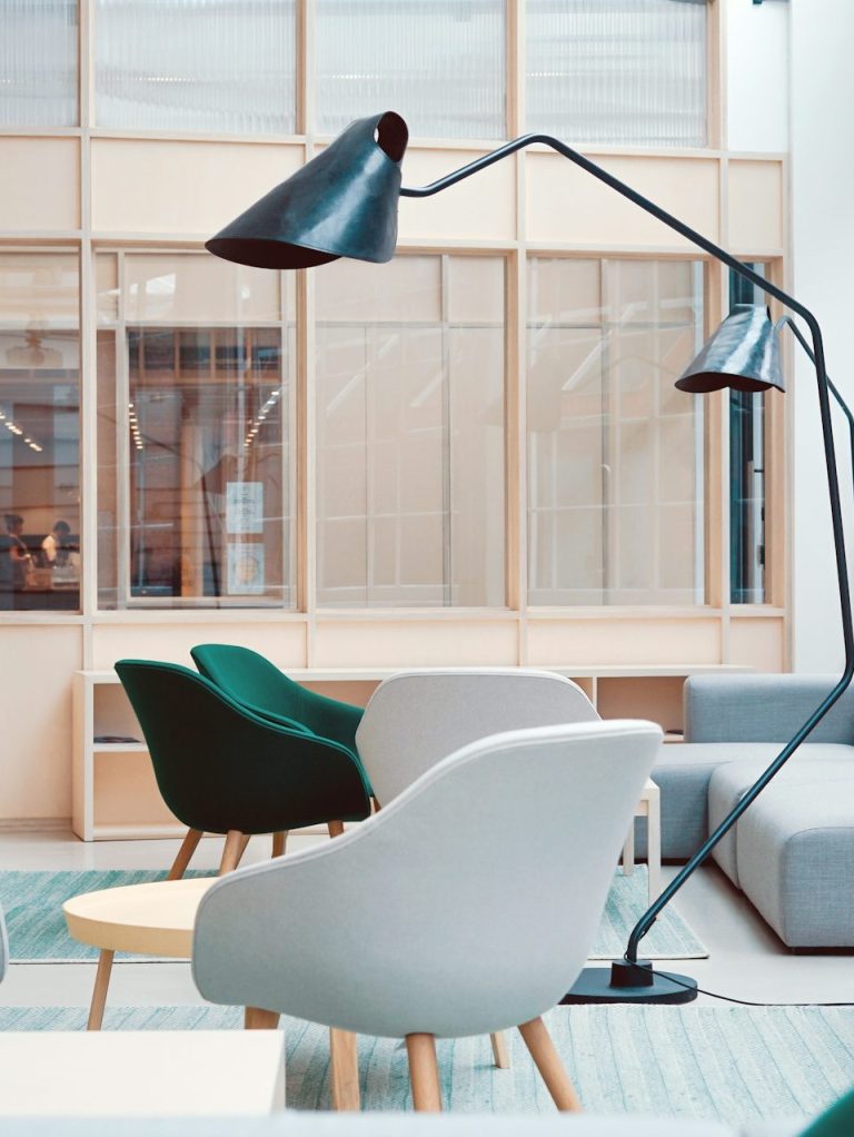 Sillas modernas en un ambiente luminoso, con una lámpara de pie elegante.